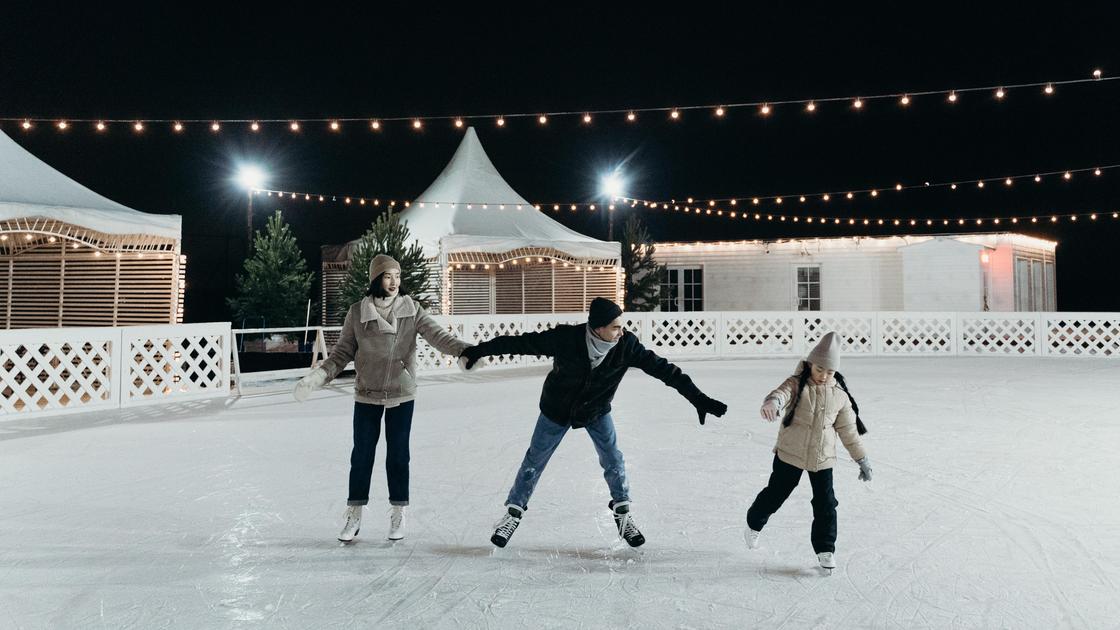 Трое человек катаются на коньках ночью