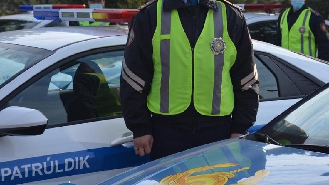 Полицейский стоит возле патрульной машины