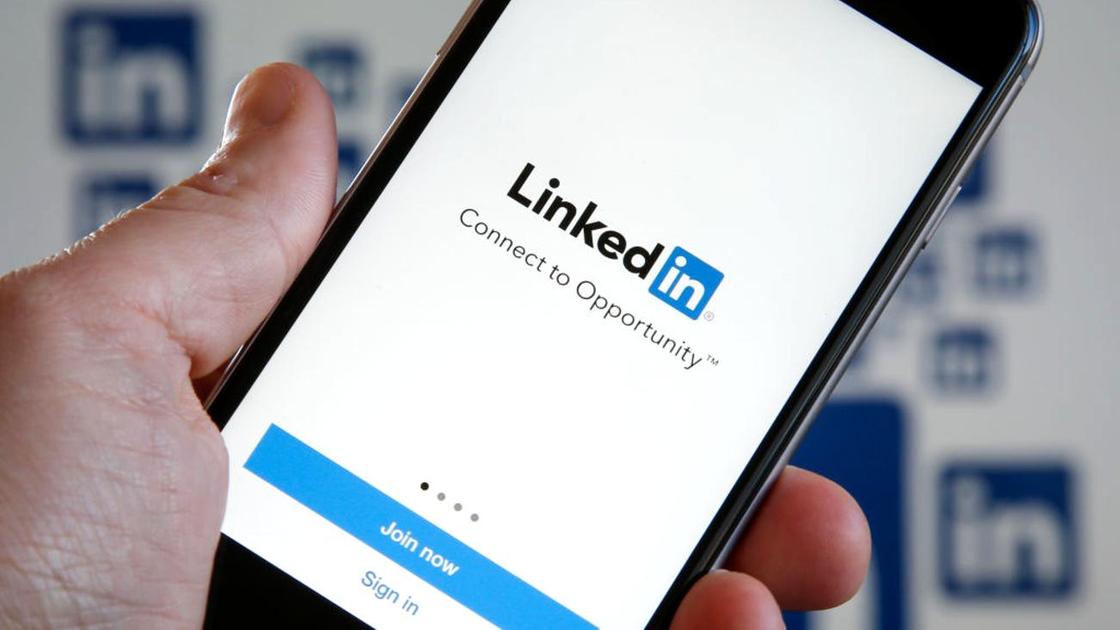 Смартфон с логотипом LinkedIn на экране держат в руке