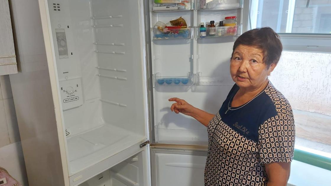 Женщина показывает холодильник