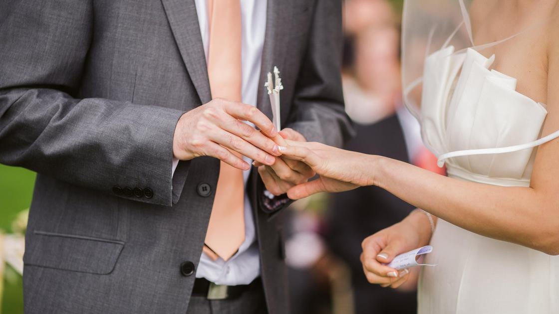 Мужчина надевает кольцо на палец невесте