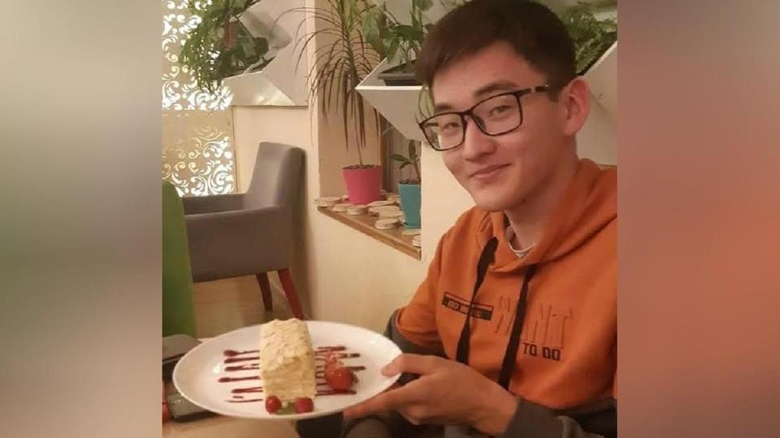 Сунгат Толебаев сидит за столом и держит пирожное Сунгат Толебаев сидит за столом и держит пирожное