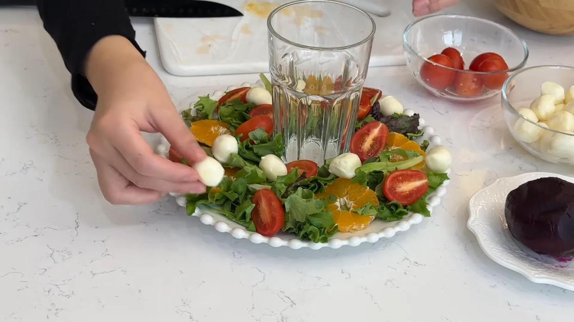 В тарелку с салатными листьями и апельсином выкладывают томаты и сыр