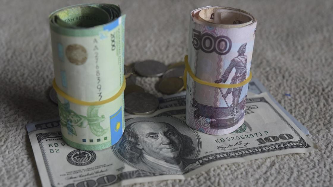 Завернутые купюры тенге и рублей стоят на долларе