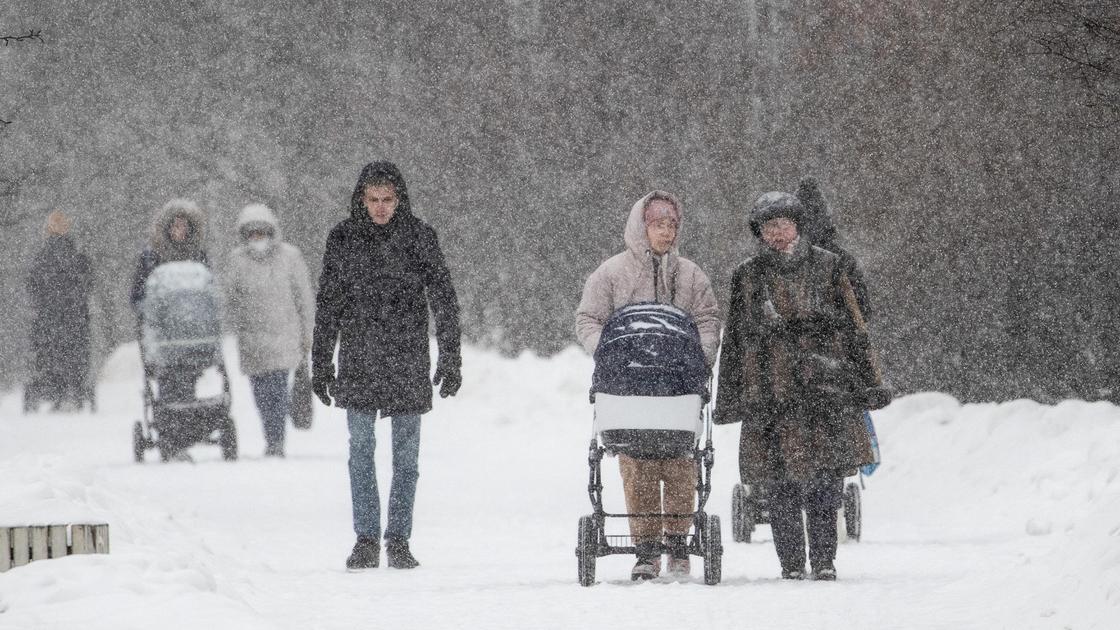 Люди идут по дороге во время снегопада