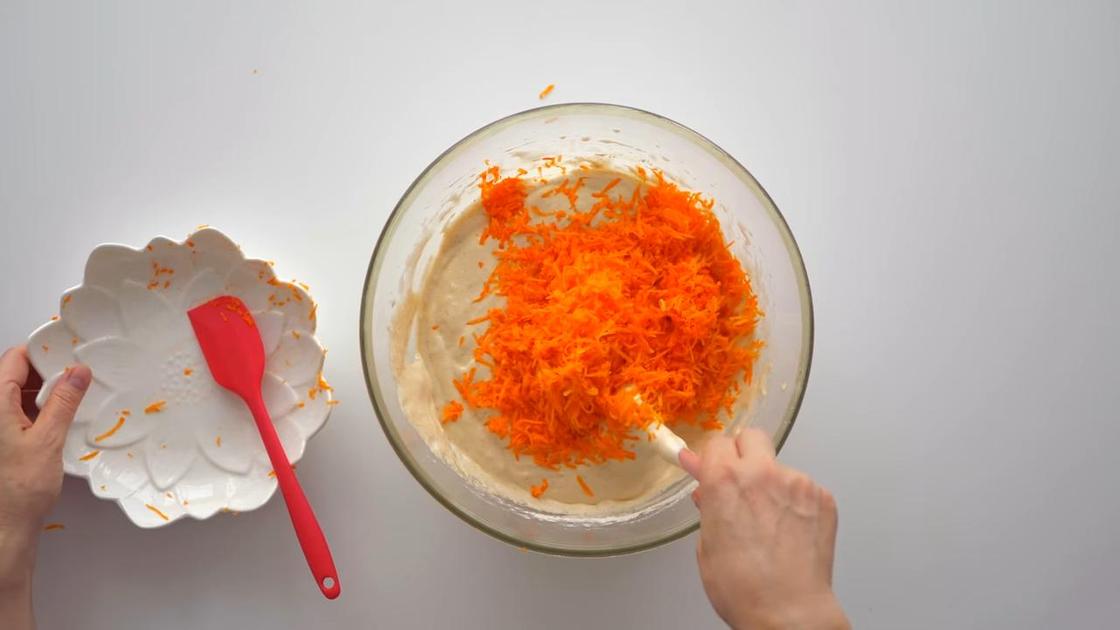 Тертую морковь вмешивают лопаткой в тесто