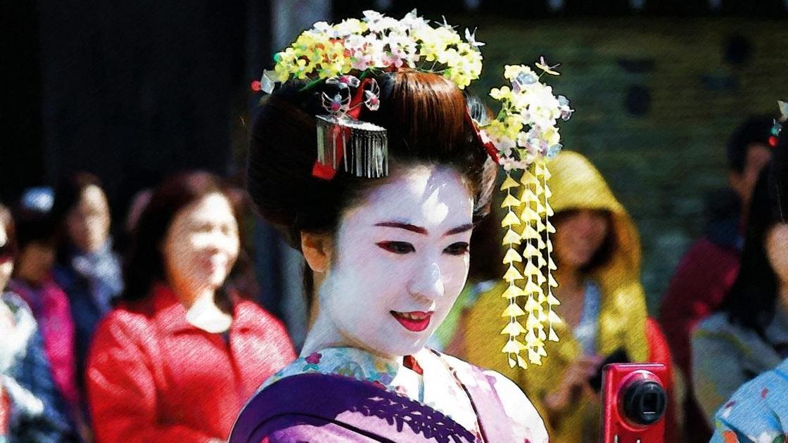 Девушка в традиционном костюме японской гейши с фотоаппаратом в руках