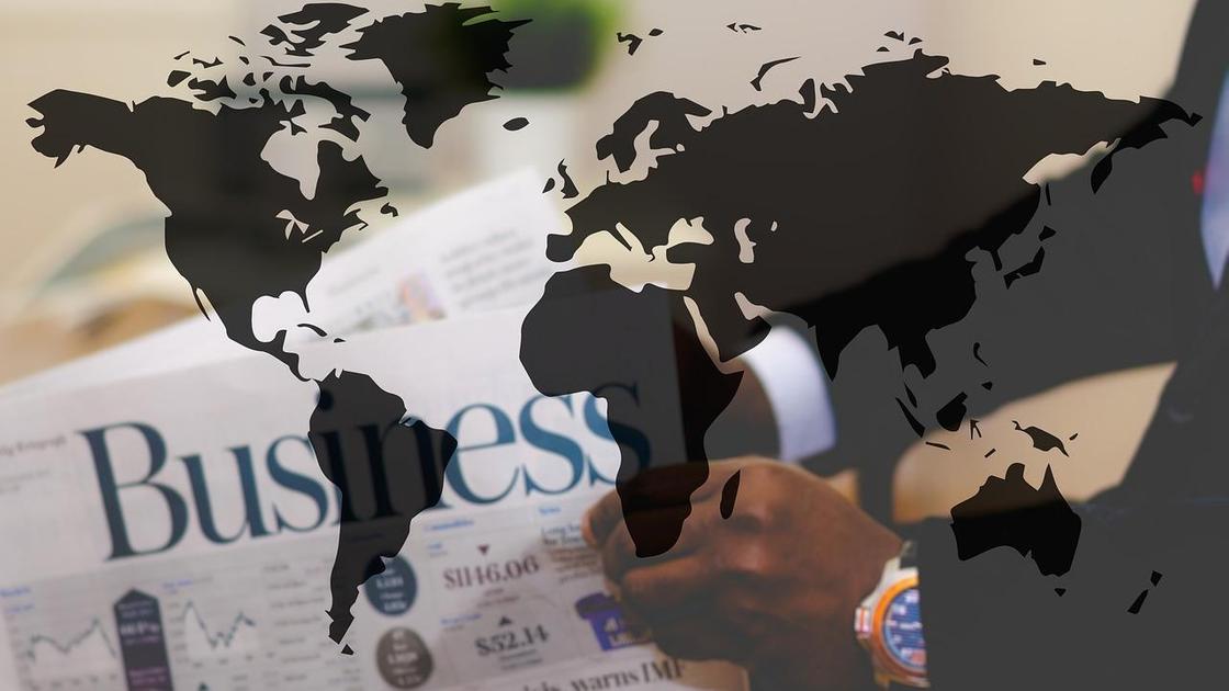 Бизнесмен с газетой в руках на фоне карты континентов