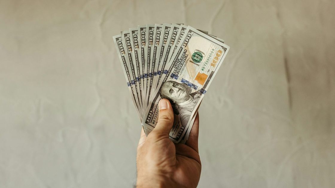 Мужчина держит доллары в руке