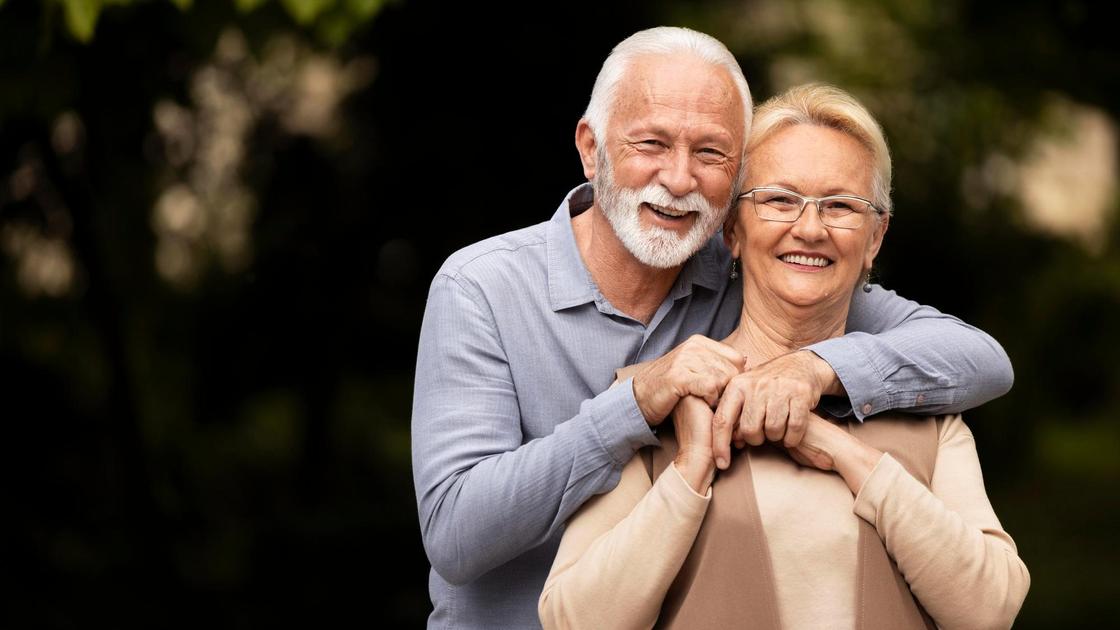 Мужчина и женщина в возрасте обнимаются и улыбаются