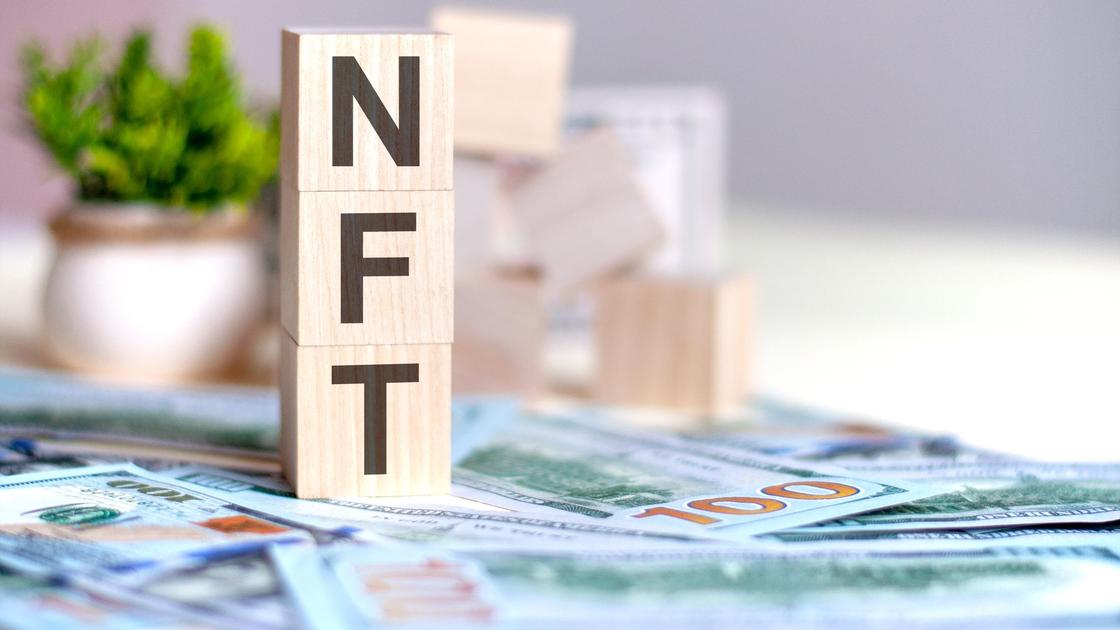 Кубики с надписью NFT стоят на долларах