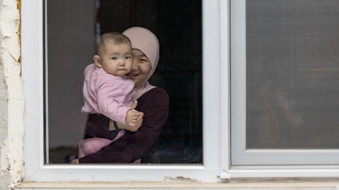Женщина с ребенком стоит у окна