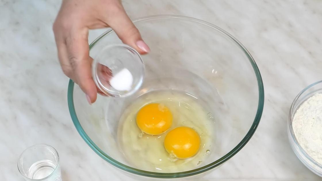 В миску с разбитыми куриными яйцами добавляют соль