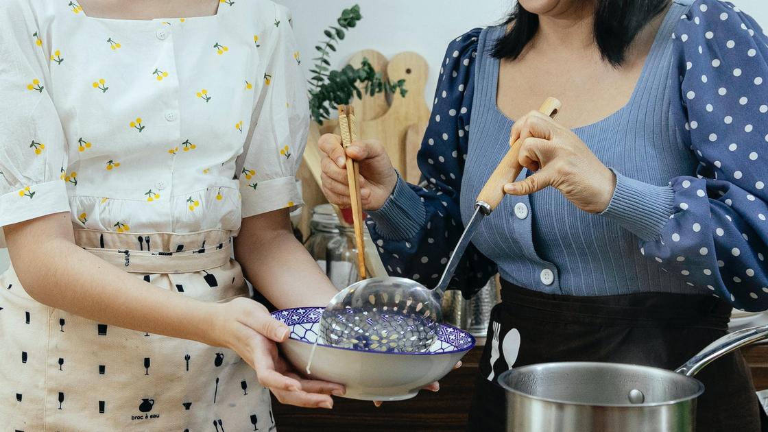 Женщины стоят у плиты на кухне