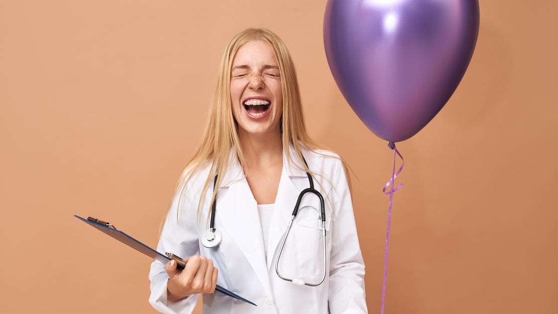 Девушка с шариком и папкой в медицинской форме смеется