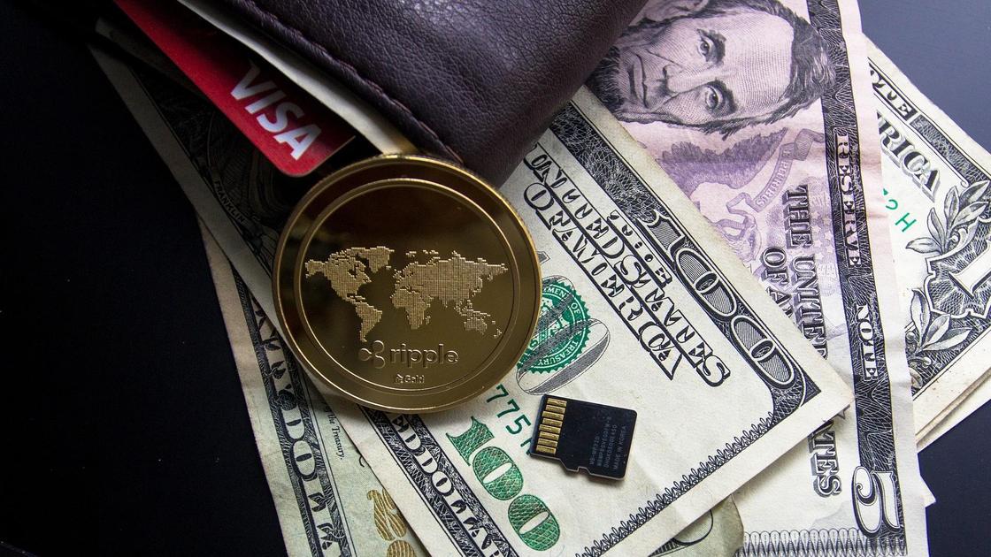 Символизирующая токен монета лежит на долларовых купюрах и кошельке