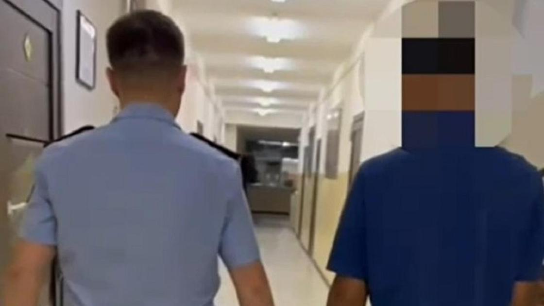 Полицейский ведет подозреваемого в Таразе Полицейский ведет подозреваемого в Таразе