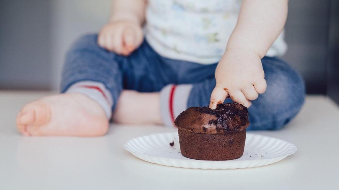 Ребенок трогает пальцем шоколадный кекс