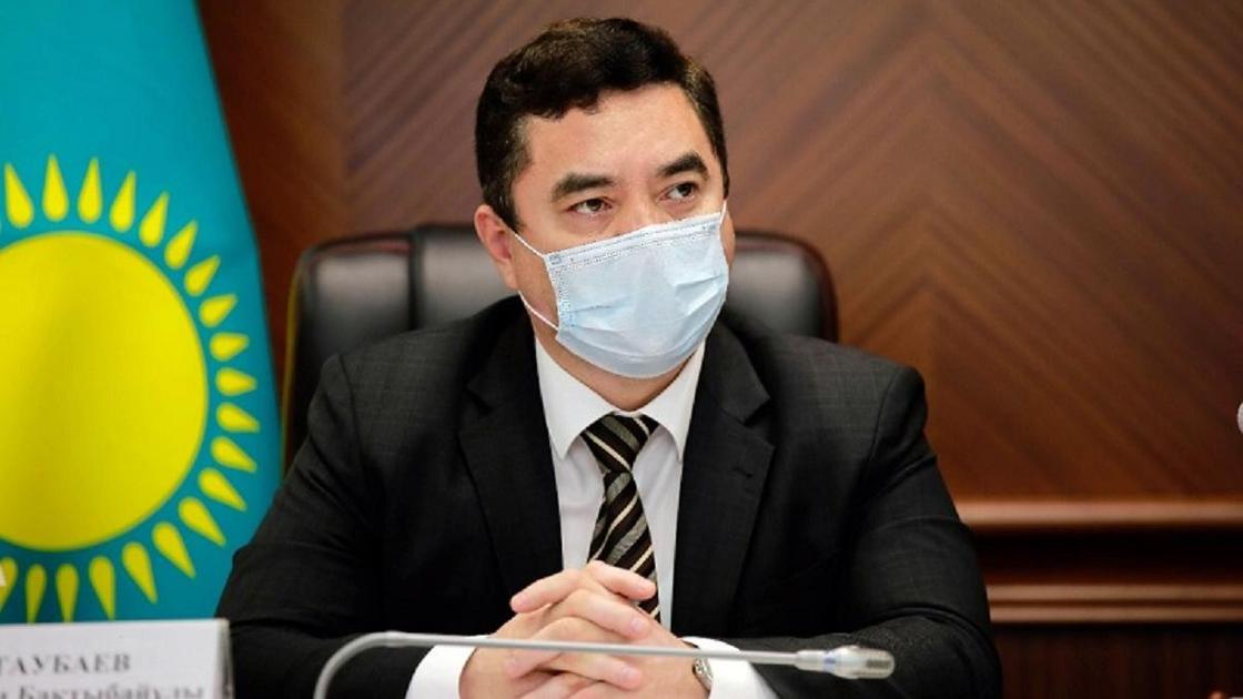 Нурлан Таубаев в маске сидит за столом