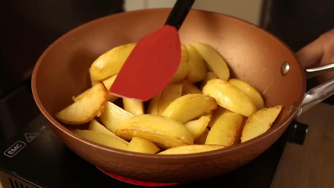 Обжаренные дольки картофеля на сковороде