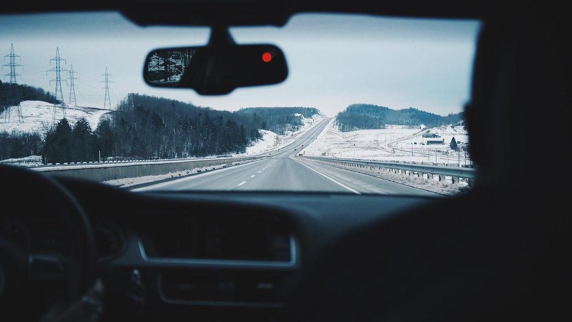 Вид на зимнюю дорогу через лобовое стекло автомобиля