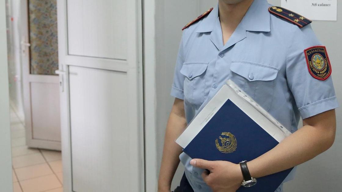 Полицейский в форме стоит в кабинете с документами в руках
