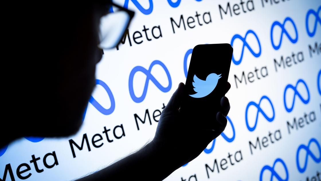 Человек держит телефон с логотипом Twitter на фоне Meta