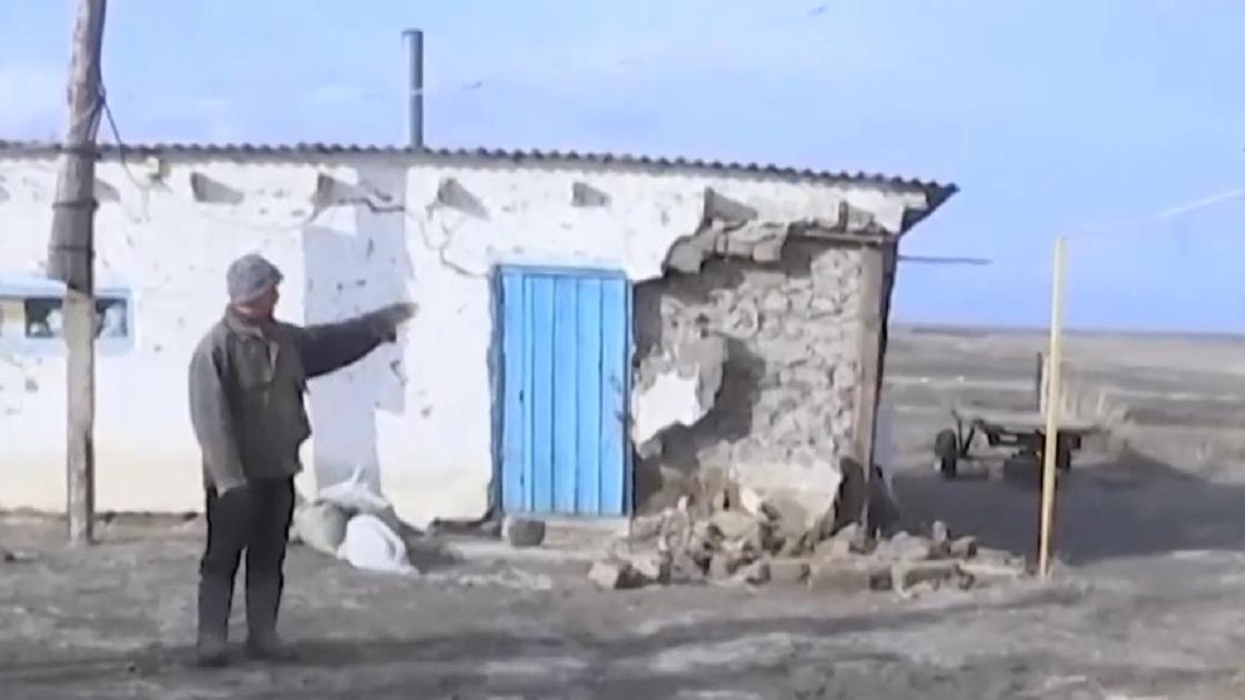 Мужчина стоит перед разрушенным домом