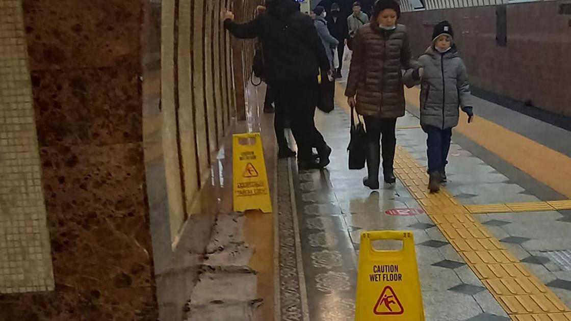 Люди идут мимо предупредительных табличек в алматинском метро