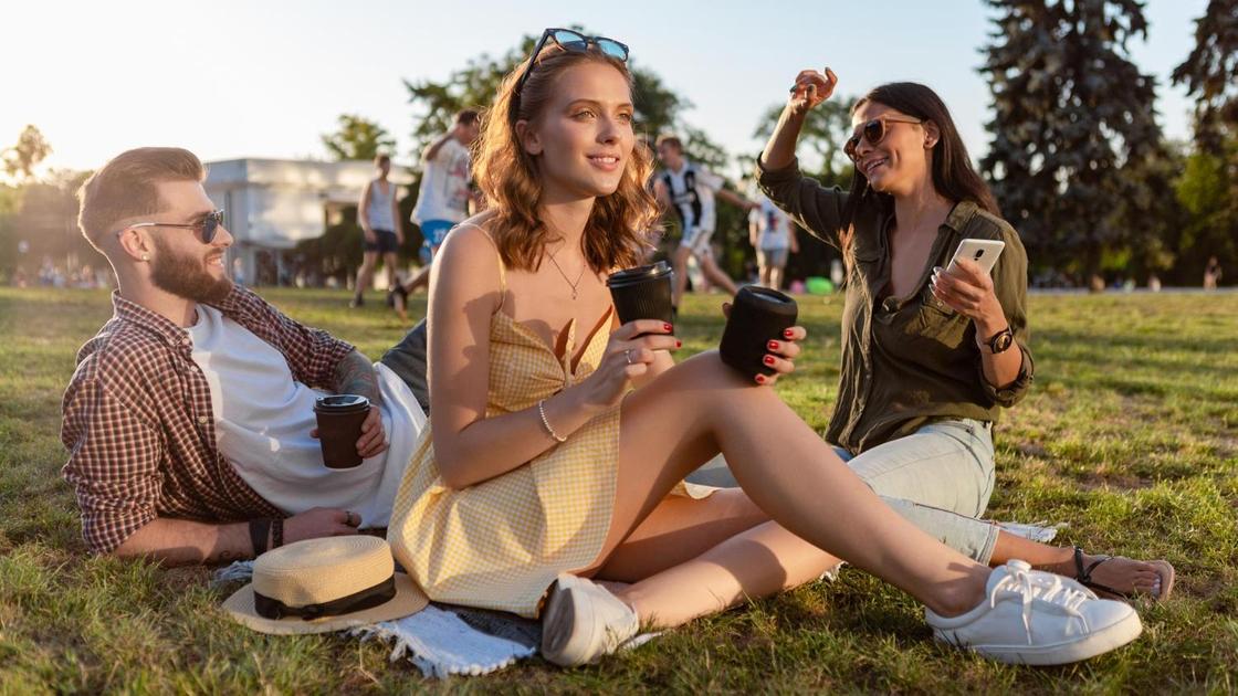 Молодые люди пьют кофе на лужайке