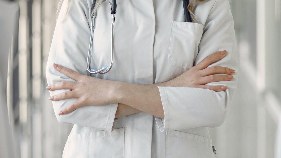 Медик стоит, сложив руки