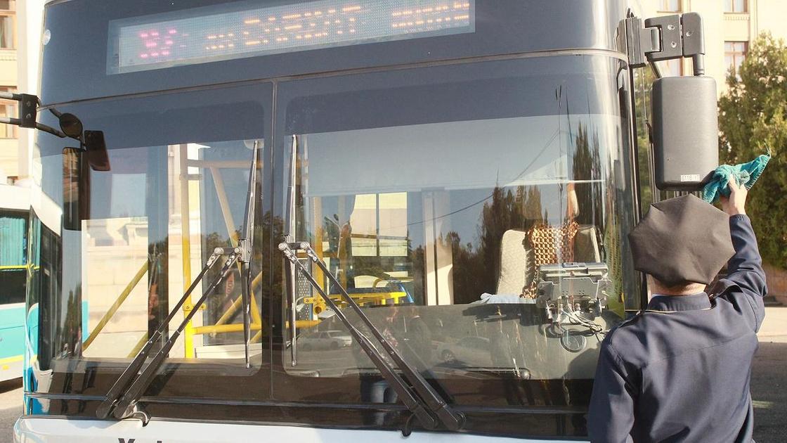 Водитель протирает зеркала у автобуса