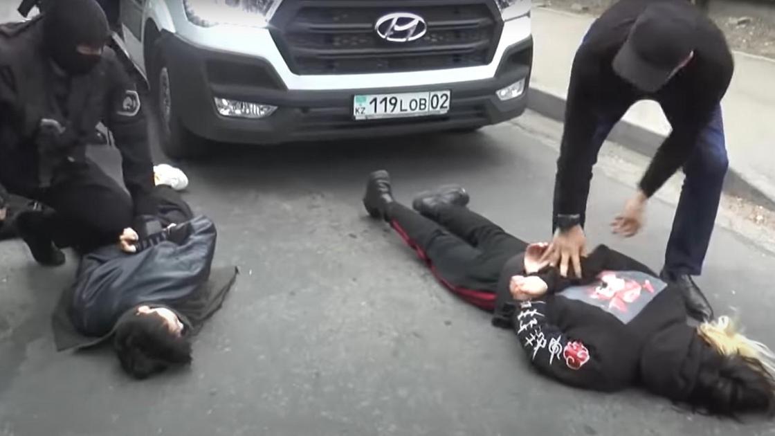 Двое мужчин лежат на земле, их задерживают силовики