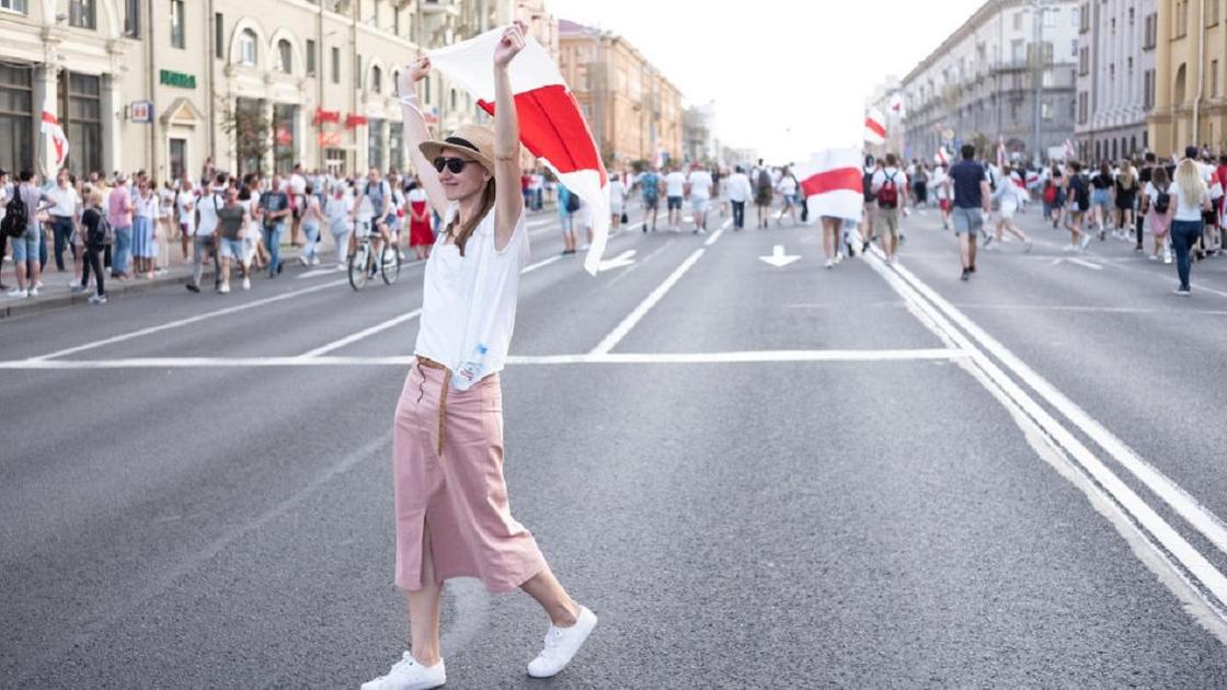 Девушка в белом на митинге в Минске с флагом