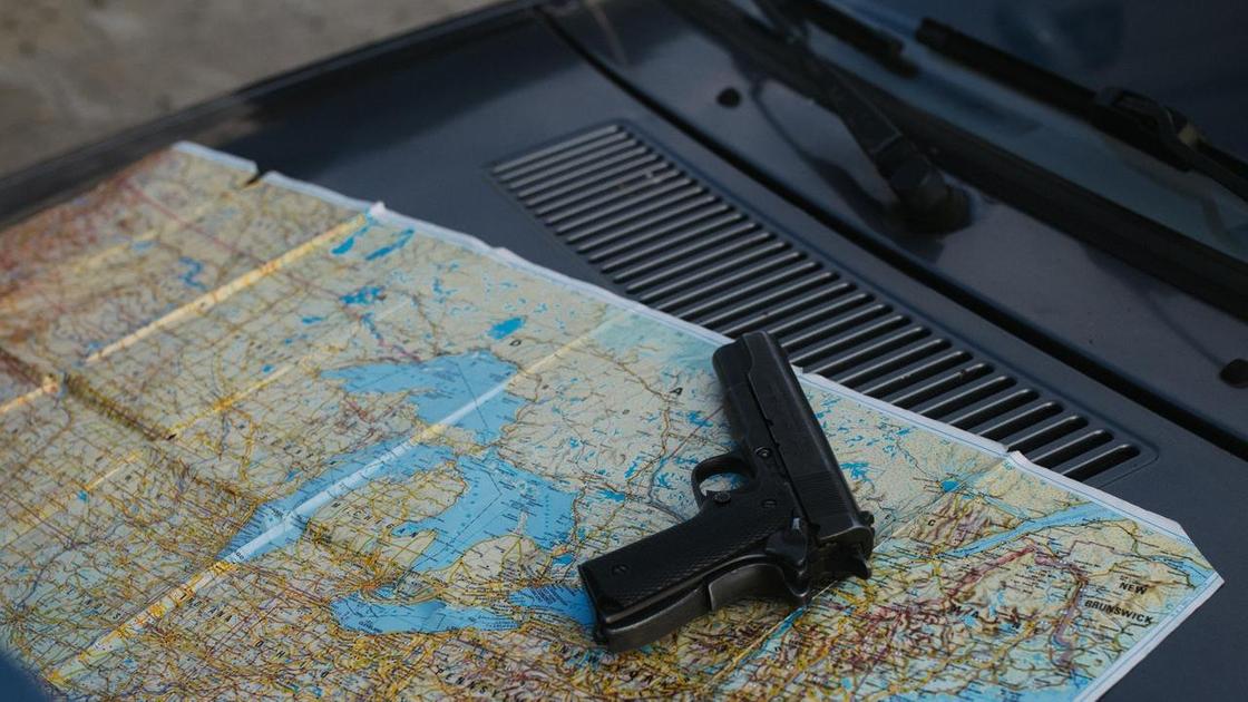 Пистолет и карта лежат на капоте автомобиля
