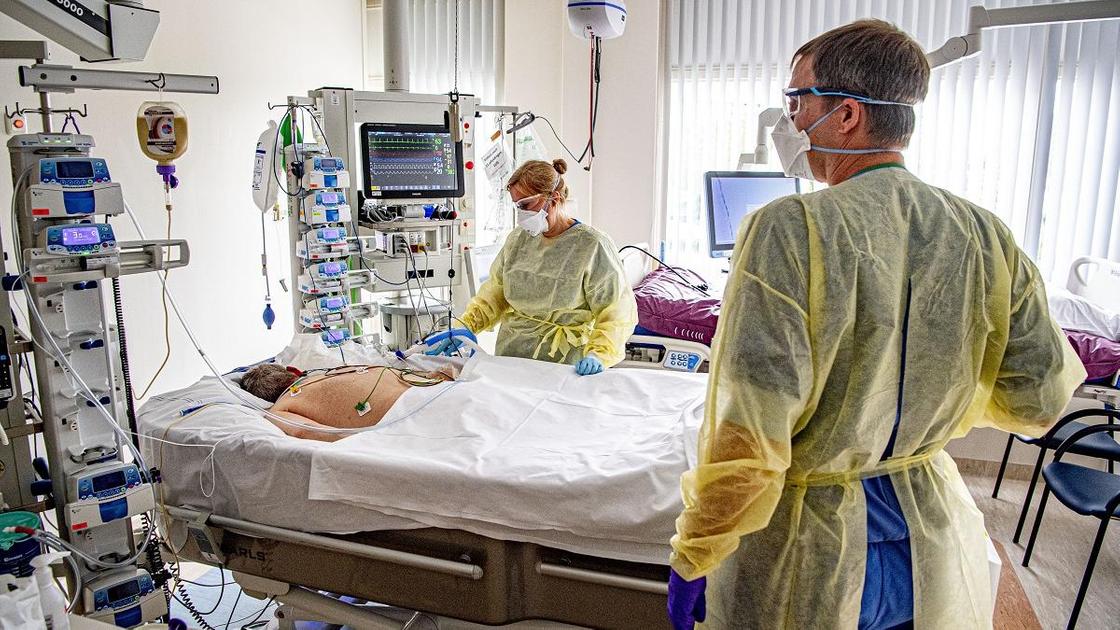 Врачи проверяют состояние пациента, лежащего на больничной койке