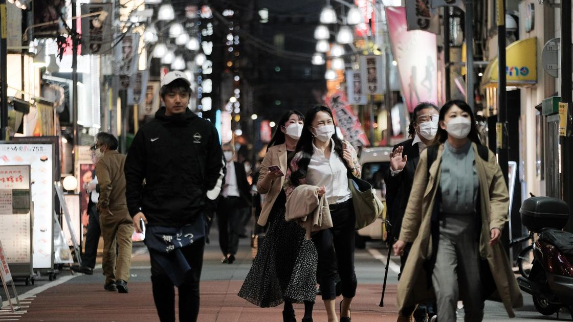 Жители Японии идут по улице в масках