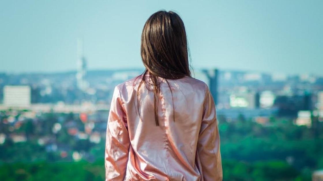 Девочка-подросток стоит спиной и смотрит на город