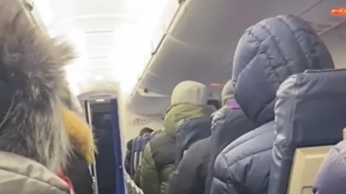 Люди в теплых куртках сидят в самолете