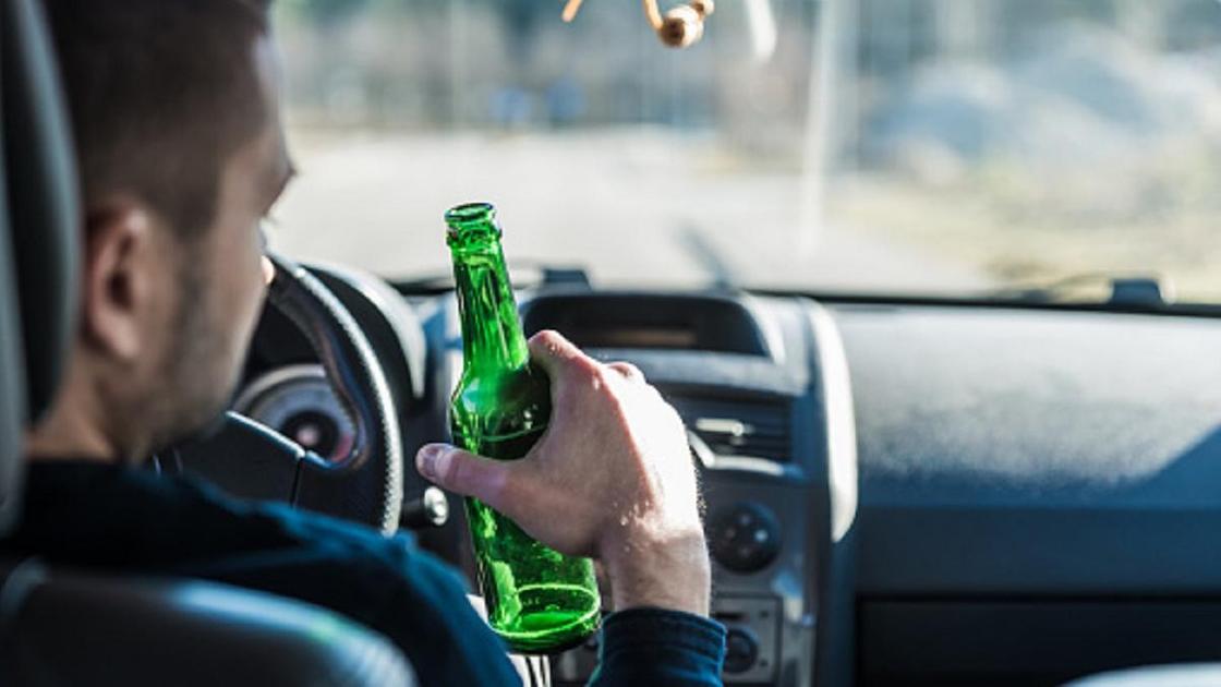 Мужчина за рулем авто с бутылкой пива в руках