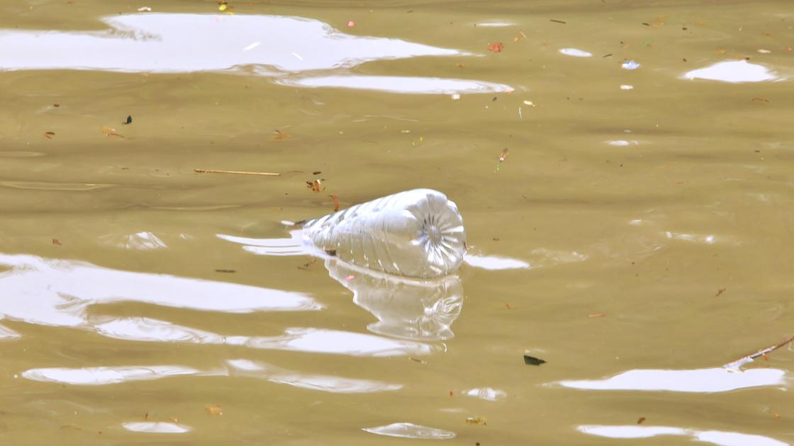 Пластиковая бутылка плавает в грязной воде