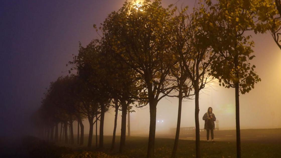 Девушка идет по улице, погруженной в туман