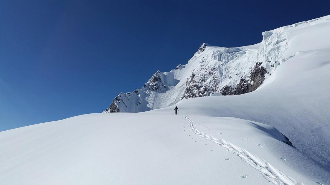 Альпинист взбирается на заснеженную гору