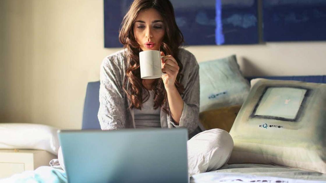 Девушка с ноутбуком и чашкой в постели