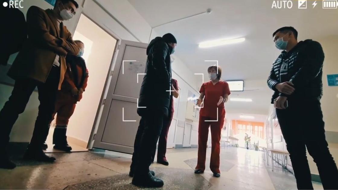 Медработница разговаривает с пациентами в коридоре больницы