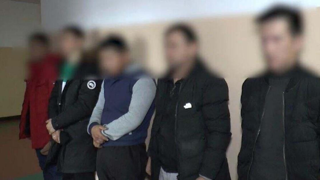Задержанные мужчины стоят возле стены