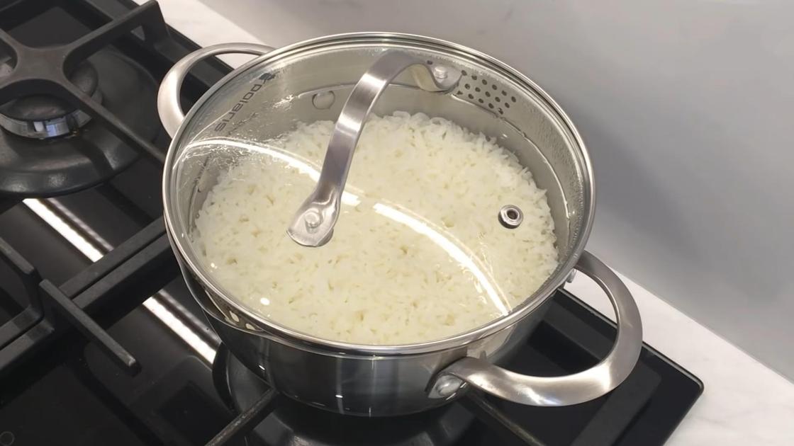 Отваренный рис в кастрюле на плите