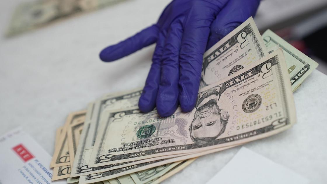 Рука в перчатках держит доллары