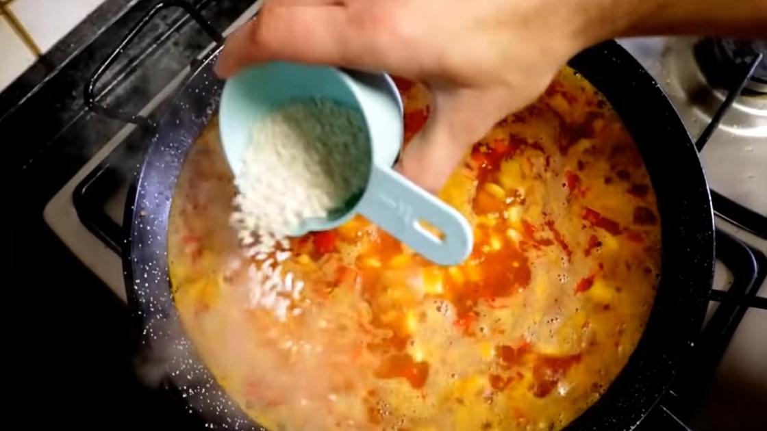 В сковороду с бульоном насыпают рис