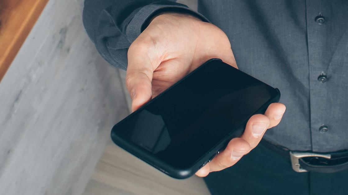 Мужчина держит в руке телефон